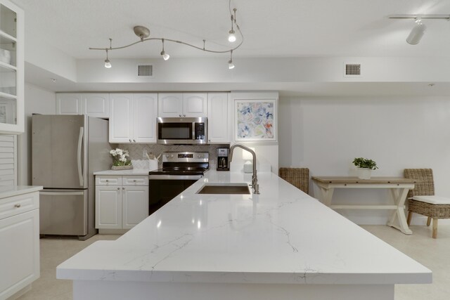 kitchen featuring a sink, stainless steel appliances, light stone counters, and visible vents