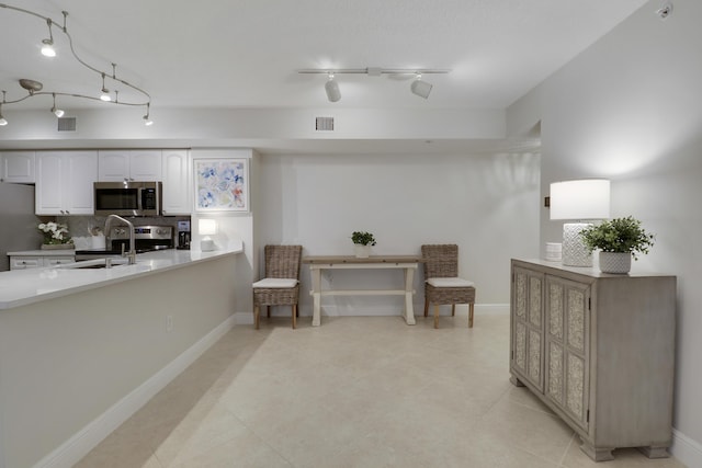 kitchen with a sink, tasteful backsplash, white cabinetry, appliances with stainless steel finishes, and light countertops