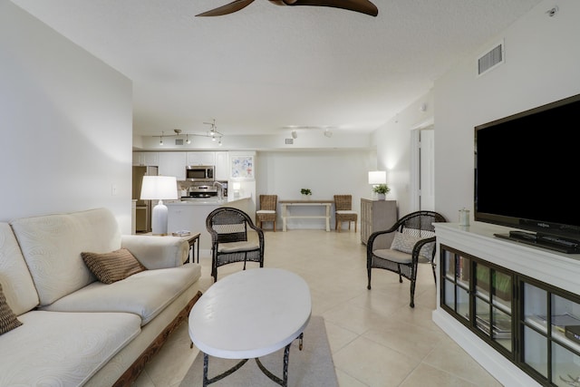 living area with visible vents, light tile patterned floors, rail lighting, a textured ceiling, and a ceiling fan