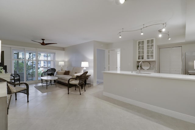 living room with light tile patterned floors, ceiling fan, and baseboards