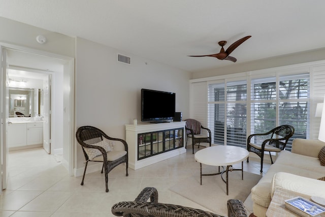 living area with light tile patterned flooring, a ceiling fan, visible vents, and baseboards