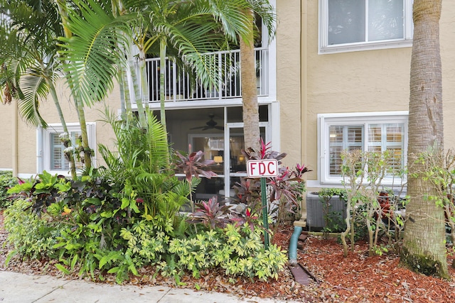 doorway to property with a balcony, central air condition unit, and stucco siding