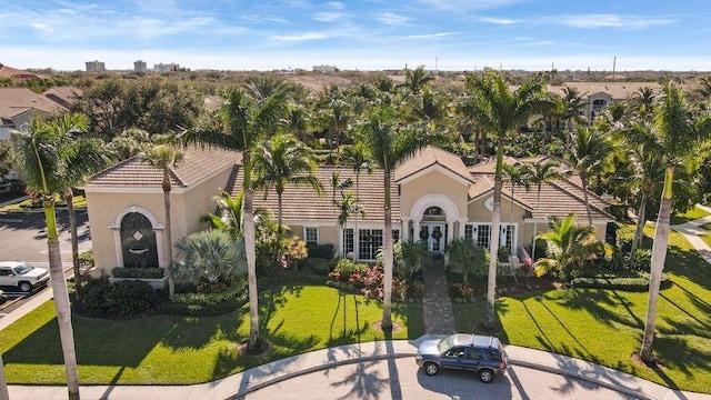 view of front of house with stucco siding, a tile roof, and a front yard