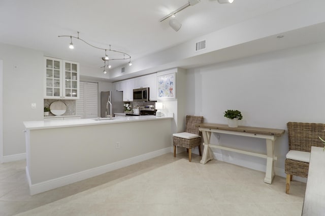 kitchen featuring decorative backsplash, white cabinets, stainless steel appliances, and glass insert cabinets