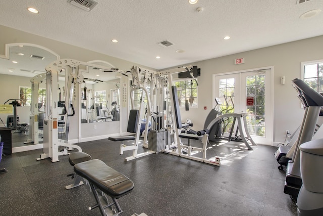 exercise room featuring visible vents, a textured ceiling, a healthy amount of sunlight, and french doors