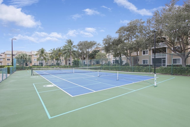 view of tennis court with a residential view and fence