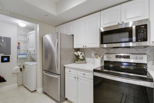 kitchen with stacked washer / dryer, backsplash, electric panel, appliances with stainless steel finishes, and white cabinets