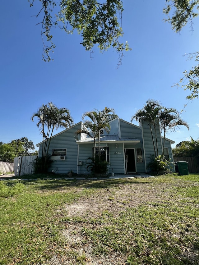 rear view of property featuring fence and a lawn