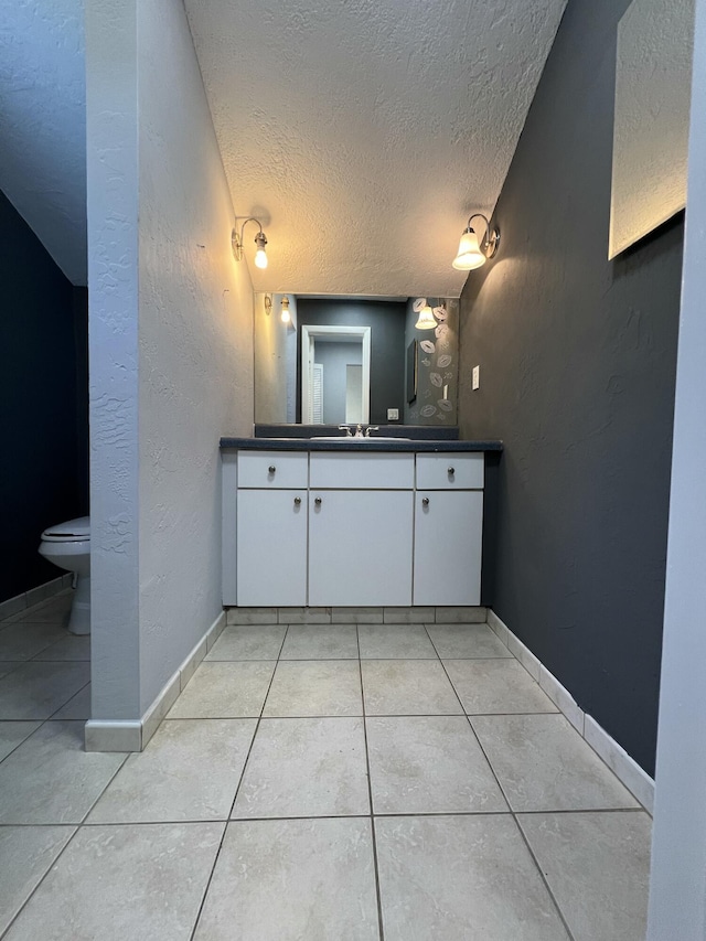 bathroom with a textured ceiling, a textured wall, tile patterned flooring, and toilet