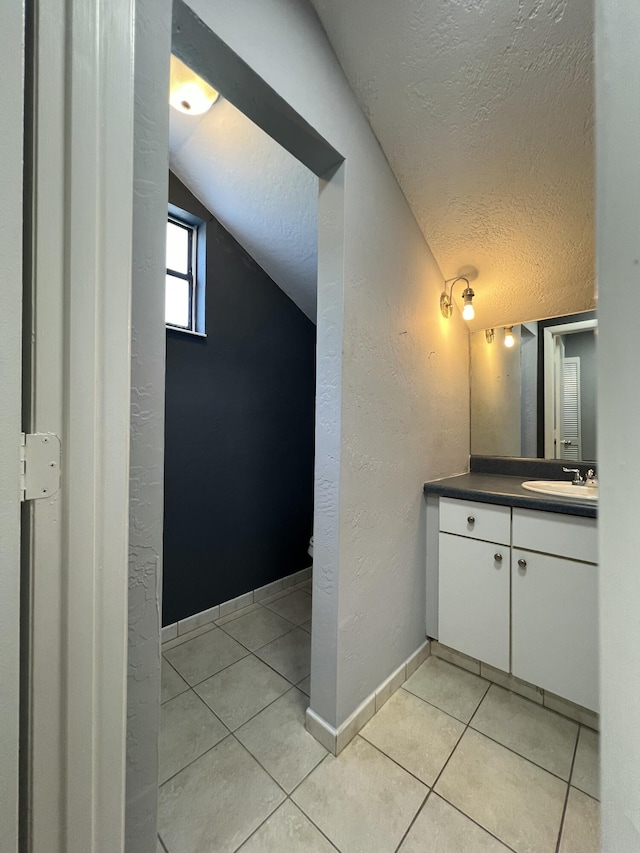 bathroom with tile patterned floors, a textured ceiling, and a textured wall