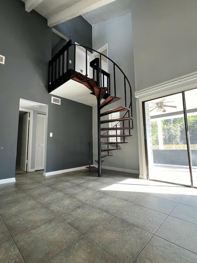 stairs featuring baseboards, a high ceiling, and visible vents