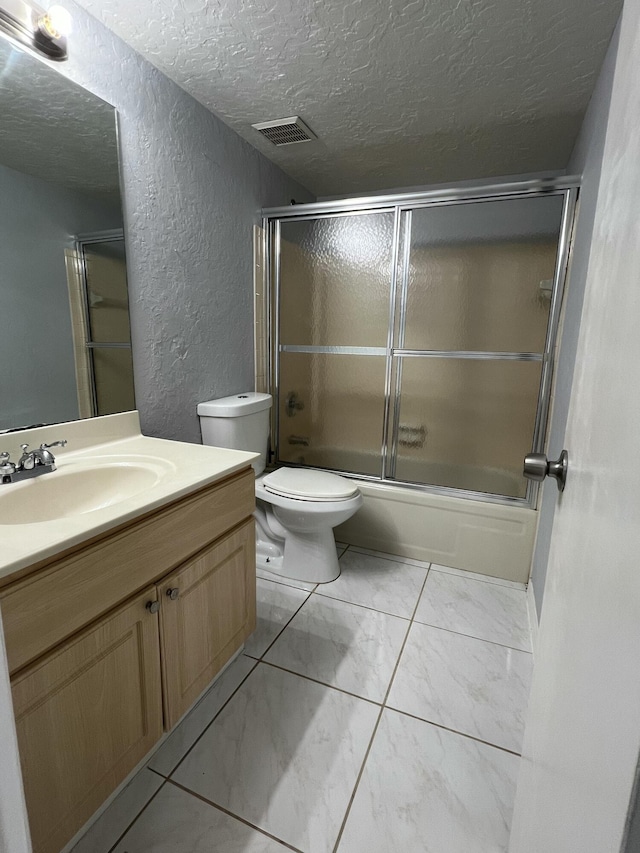 bathroom featuring a textured ceiling, a textured wall, shower / bath combination with glass door, vanity, and visible vents