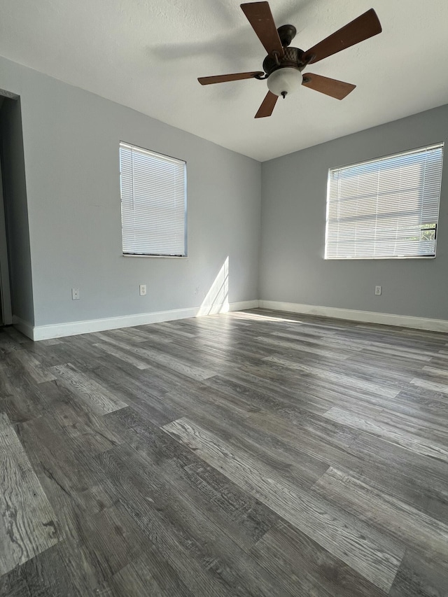 unfurnished room featuring ceiling fan, baseboards, and dark wood-type flooring