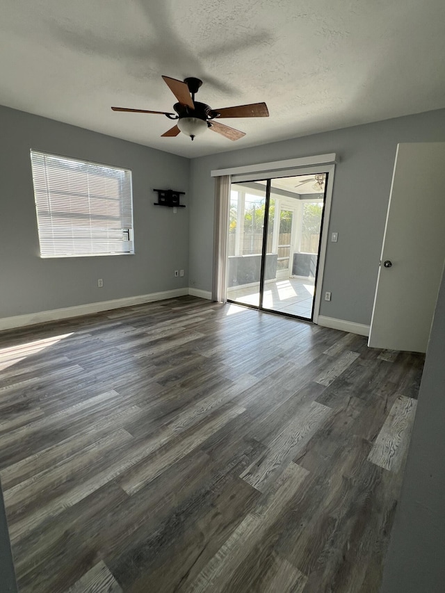 spare room with a ceiling fan, dark wood finished floors, a textured ceiling, and baseboards