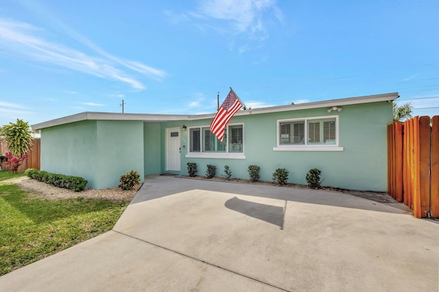 ranch-style house featuring fence and stucco siding