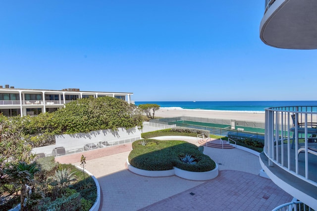 view of patio / terrace with a water view, a balcony, and a view of the beach