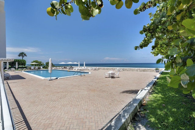 community pool with a patio area and a water view