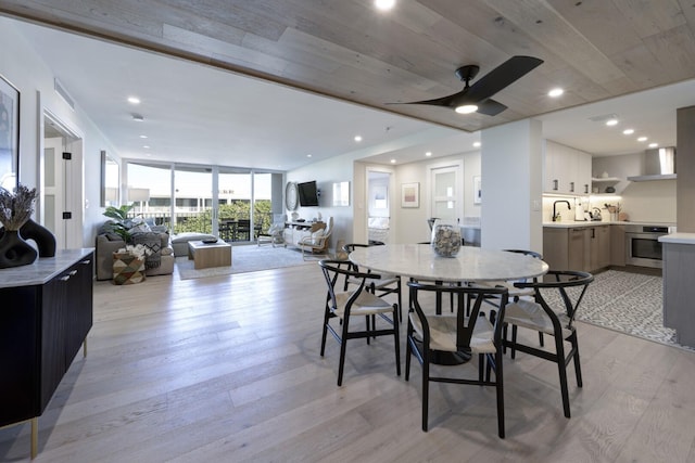 dining room featuring a wall of windows, recessed lighting, ceiling fan, and light wood-style flooring