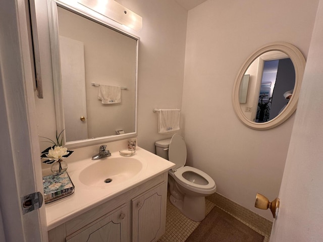 half bathroom with vanity, toilet, and tile patterned floors