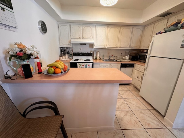 kitchen featuring tasteful backsplash, light countertops, white appliances, a peninsula, and under cabinet range hood