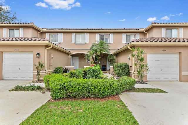 multi unit property featuring a garage, a tiled roof, concrete driveway, and stucco siding