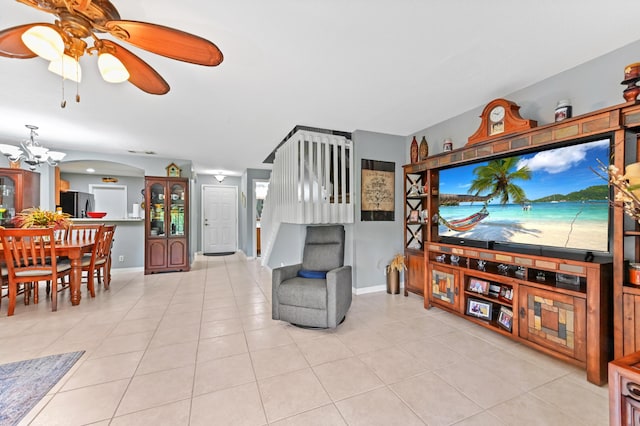 living area with ceiling fan with notable chandelier, baseboards, and light tile patterned flooring