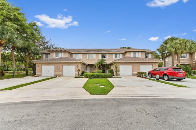 view of property featuring a garage, concrete driveway, a tiled roof, and stucco siding