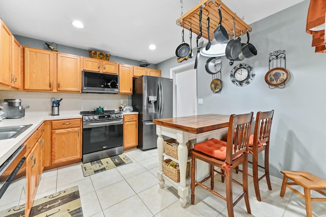 kitchen featuring baseboards, appliances with stainless steel finishes, light tile patterned flooring, light countertops, and recessed lighting