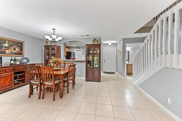 dining room with light tile patterned floors, visible vents, stairway, an inviting chandelier, and baseboards