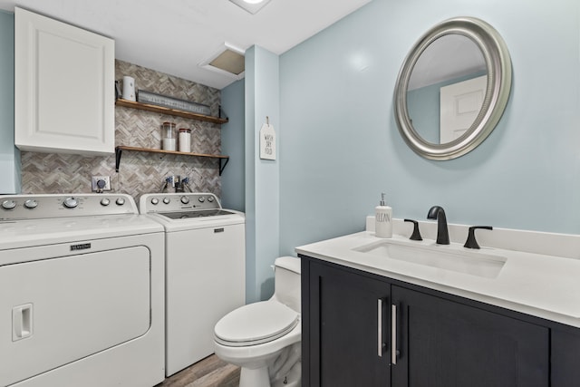 bathroom with toilet, wood finished floors, vanity, backsplash, and washing machine and clothes dryer