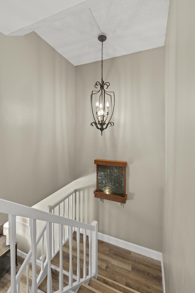 stairs featuring a textured ceiling, baseboards, and wood finished floors