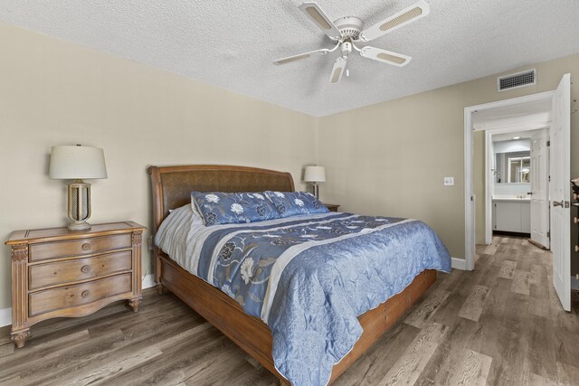 bedroom with baseboards, visible vents, a ceiling fan, wood finished floors, and a textured ceiling