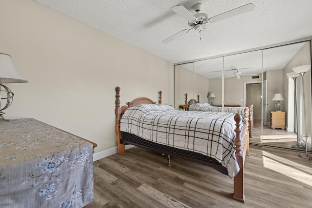 bedroom featuring a textured ceiling, ceiling fan, wood finished floors, and baseboards