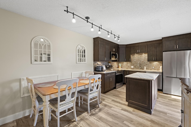 kitchen with dark brown cabinetry, light wood-style floors, stainless steel appliances, and a sink