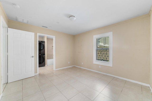 1204 Easter Ave, Fort Pierce, FL 34950 - empty room with stacked washing machine and dryer, light tile patterned floors, baseboards, and ornamental molding