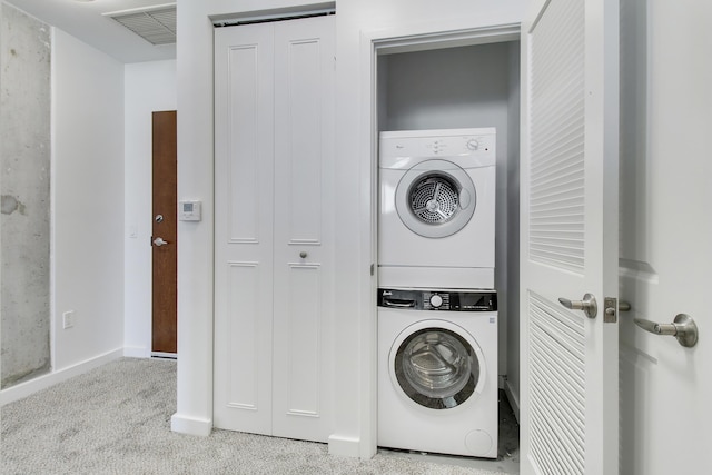 washroom featuring laundry area, visible vents, baseboards, stacked washer / drying machine, and carpet