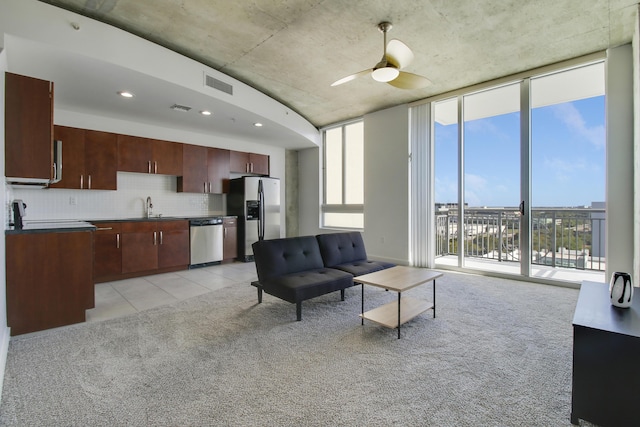 living area with light carpet, expansive windows, visible vents, and a ceiling fan