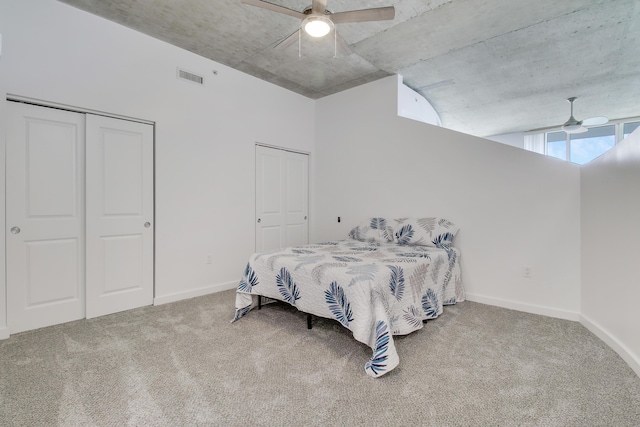 bedroom featuring ceiling fan, visible vents, baseboards, multiple closets, and carpet