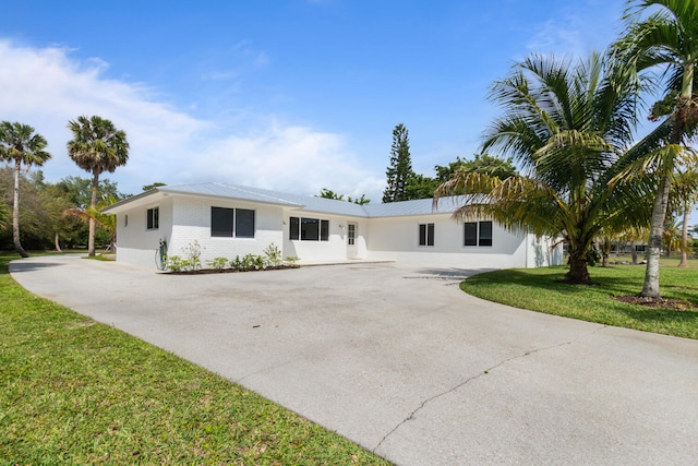 single story home featuring concrete driveway, a front lawn, and brick siding