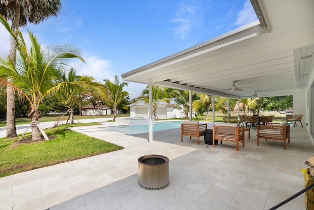 view of patio with a ceiling fan, outdoor dining space, a pool with connected hot tub, and an outbuilding