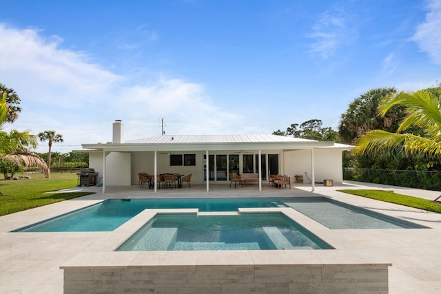 rear view of house with a pool with connected hot tub, a patio area, fence, and a chimney