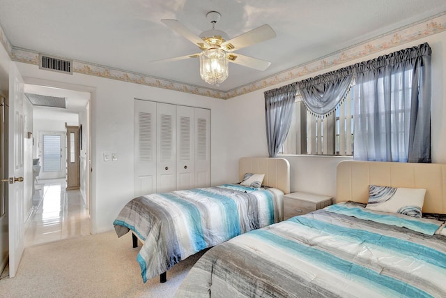 bedroom with carpet floors, visible vents, a ceiling fan, a closet, and attic access