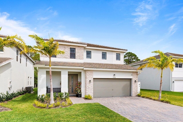 traditional-style house featuring an attached garage, central air condition unit, a front lawn, and decorative driveway