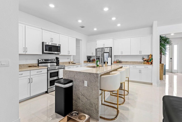 kitchen with white cabinetry, a center island with sink, visible vents, and stainless steel appliances