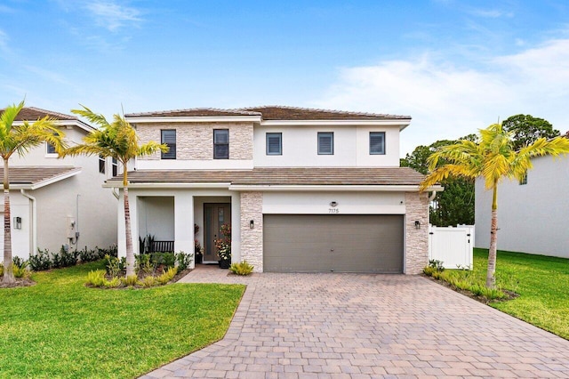 traditional-style home with stone siding, decorative driveway, a front yard, and stucco siding