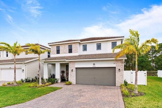 traditional-style house with an attached garage, fence, decorative driveway, a front yard, and stucco siding