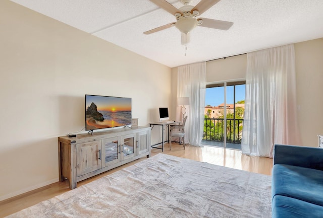 living room featuring ceiling fan, wood finished floors, baseboards, and a textured ceiling