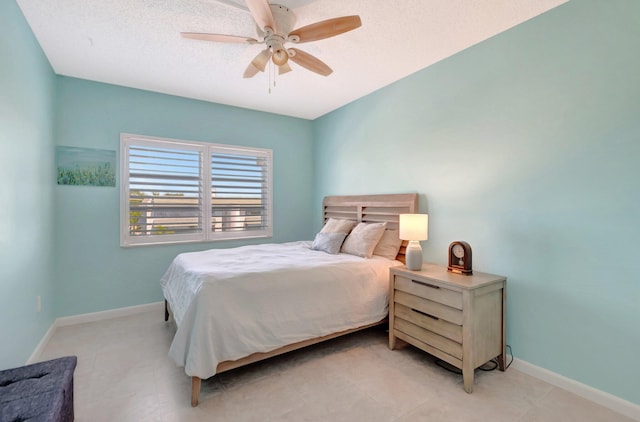 bedroom with ceiling fan, a textured ceiling, and baseboards