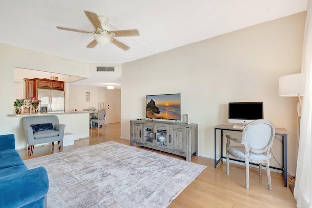 living area with a ceiling fan, visible vents, and light wood finished floors