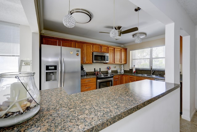 kitchen with stainless steel appliances, a sink, brown cabinets, dark countertops, and crown molding